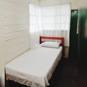 Cama blanca en habitación con ventana en Hotel Lomas del Paiyü, en Puerto Nariño