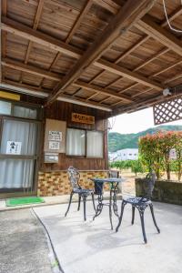 un patio con 2 sillas, una mesa y un cartel en すなだの家, en Uwajima