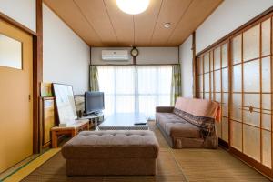 uma sala de estar com um sofá e uma televisão em すなだの家 em Uwajima