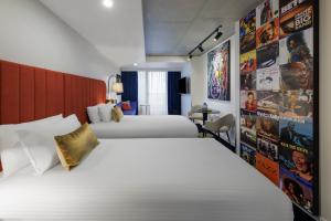 a hotel room with two beds and posters on the wall at The Jazz Corner Hotel Melbourne in Melbourne
