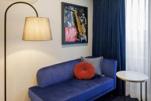 a blue couch with a red pillow on it at The Jazz Corner Hotel Melbourne in Melbourne