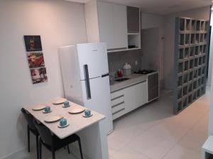 a kitchen with a table and a white refrigerator at FLATS TAVARES ARAUJO 202 in Garanhuns