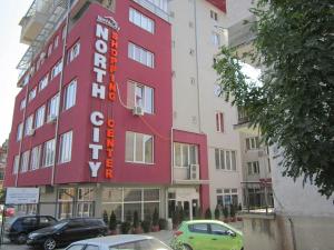 a building with a red sign on the side of it at Hotel North City in Mitrovicë