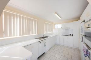 une cuisine blanche avec des placards blancs et une fenêtre dans l'établissement 1 6 Convent Lane-LJHooker Yamba, à Yamba