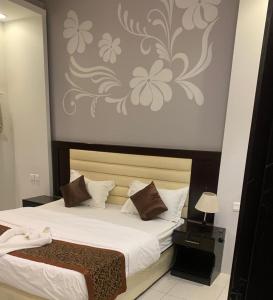 a bedroom with a bed and a wall with a flower mural at ركن الهدوء in Muhayil