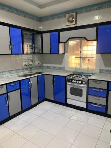 a large kitchen with blue cabinets and a stove at ركن الهدوء in Muhayil