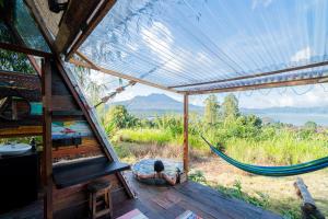 eine Person, die in einer Hängematte in einem Haus liegt in der Unterkunft Cloud Hills Glamping in Kintamani