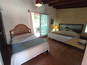 ein Schlafzimmer mit zwei Betten und einem großen Fenster in der Unterkunft Hotel Posada Comala in Comala + 52 Fotos