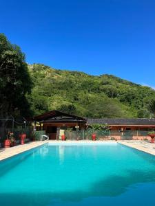 a large blue swimming pool in front of a mountain at Hostel Finca La Gordita in Calabazo