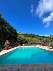 a large blue swimming pool with a mountain in the background at Hostel Finca La Gordita in Calabazo