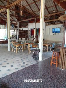 a group of tables and chairs in a building at Happy Days Guest House in Ko Kood