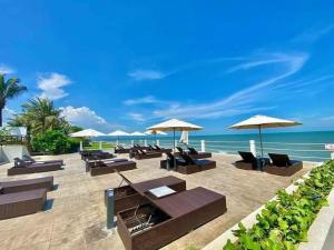 a beach with chairs and umbrellas and the ocean at Aria Resort- Căn hộ nghỉ dưỡng tầng 8 hướng biển, hồ bơi sát cạnh bãi tắm riêng (miễn phí) in Xa Thang Nhut
