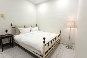 a bedroom with a large white bed with a lamp at The Penggawa Homestay - 3 comfortable bedrooms in Johor Bahru