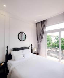 ein weißes Schlafzimmer mit einem großen Bett und einem Fenster in der Unterkunft The Fancy House in Quy Nhon