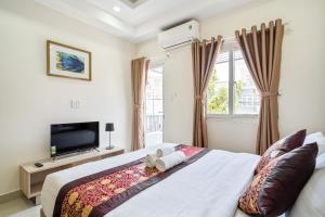 a bedroom with a bed and a tv and windows at AVIVA RESIDENCES in Thuan An