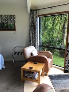 sala de estar con silla, mesa y ventana en Lakehouse Studio en Kerikeri