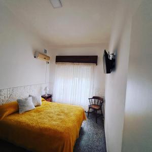 1 dormitorio con 1 cama amarilla y 1 silla en Chalet La Mambu en Mar de Ajó