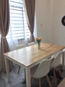 a wooden table with white chairs and a vase of flowers on it at Rooma Singgah Homestay @ Cherating in Kuantan