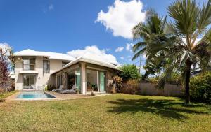a house with a swimming pool and a palm tree at VILLA CHAMAREL in Flic-en-Flac