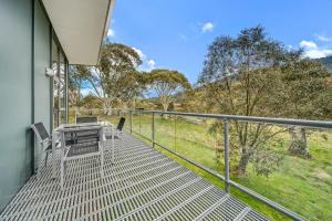 un balcone di una casa con tavolo e sedie di Ecocrackenback 4 Sustainable chalet close to the slopes a Crackenback