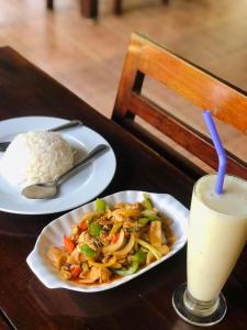 a plate of food with rice and a drink on a table at Khao Sok Nung House in Khao Sok
