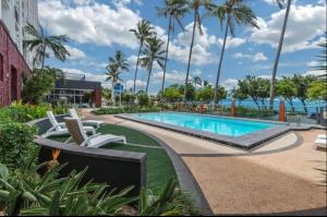 a pool at a resort with palm trees at Seafront Studio The Strand in North Ward