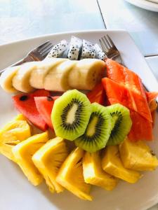 a plate of fruit with a hot dog and kiwis and pineapple at Khao Sok Nung House in Khao Sok