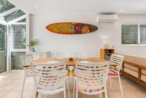 ヌーサヘッズにあるKareela Court 4 Kareela Avenue 14のダイニングルーム(テーブル、椅子、壁にサーフボード付) +4枚の写真