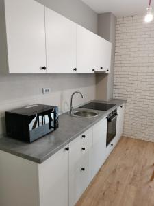 a kitchen with white cabinets and a sink at Apartament incantator Iasi Copou in Iaşi