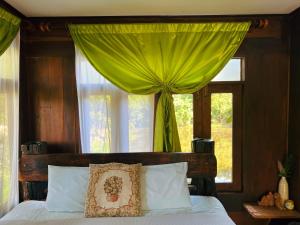a bedroom with a bed with a green curtain at Sukhothai City Resort in Sukhothai