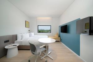 a bedroom with a bed and a table and a tv at GO! Hotel Bowin at Robinson Lifestyle Bowin in Si Racha