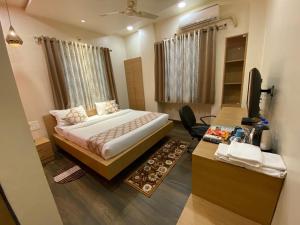 a bedroom with a bed and a desk with a television at WOWstops VENUS in Pune