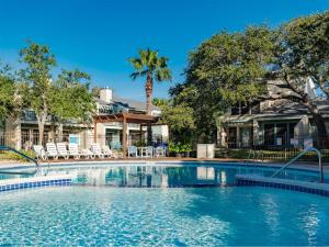 a swimming pool with chairs and a palm tree at Sea La Vie in Rockport
