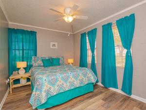 a bedroom with a bed and blue curtains and a fan at Sea Gun Bayhome #128 in Rockport