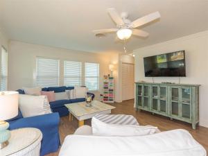 - un salon avec un canapé bleu et un ventilateur de plafond dans l'établissement Tejas Tides, à City-by-the Sea