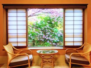 two chairs and a table in front of a window at Hanafubuki in Ito