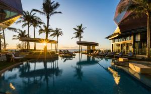a resort pool with palm trees and a building at The Langham, Gold Coast and Jewel Residences in Gold Coast