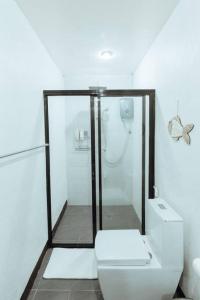 a white bathroom with a shower and a toilet at BayayTagoSiargao in General Luna