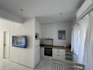 Il comprend une cuisine blanche avec des placards blancs et une télévision murale. dans l'établissement Modern 1-bedroom apartment in the city center, à Thessalonique