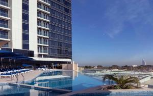een groot zwembad naast een hoog gebouw bij ON OFF HH-AVANI HOTEL-3BR -Full Palm View in Dubai