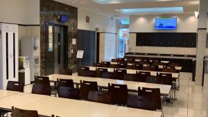 Toyoko Inn Saitama Iwatsuki Ekimae في سايتاما: قاعة محاضرات فيها طاولات وكراسي وشاشة