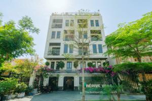 a white building with flowers in front of it at Dérive Boutique Villa & Apartment Da Nang in Danang
