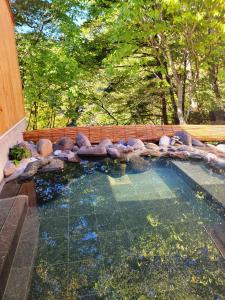 a large pool of water with rocks in a backyard at K's House Nikko - Kinugawa Onsen Hostel in Nikko