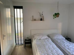 1 dormitorio blanco con 2 camas y ventana en Modern villa in Harderwold with garden, en Zeewolde