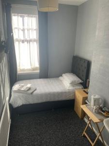 a small bedroom with a bed and a window at Shakers Inn in Harwich