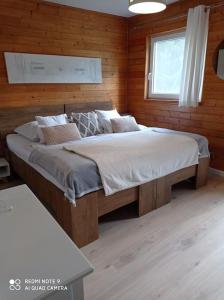 sypialnia z dużym łóżkiem w drewnianej ścianie w obiekcie Basiówka nad jeziorem w Boszkowie