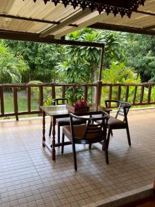 een tafel en 2 stoelen op een patio bij Traditional Thai house บ้านเรือนไทย ใกล้หาดระยอง in Ban Chak Phai