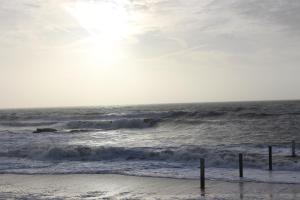 una playa con olas en el océano con el sol en el cielo en CLAIRE MARINE PORNIC, en Pornic 3 fotos más