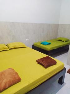 two beds in a room with yellow sheets at Homestay Premium 45 in Jepara