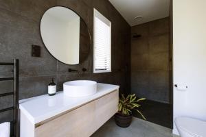 a bathroom with a white sink and a mirror at Modern Raglan Hideaway in Raglan